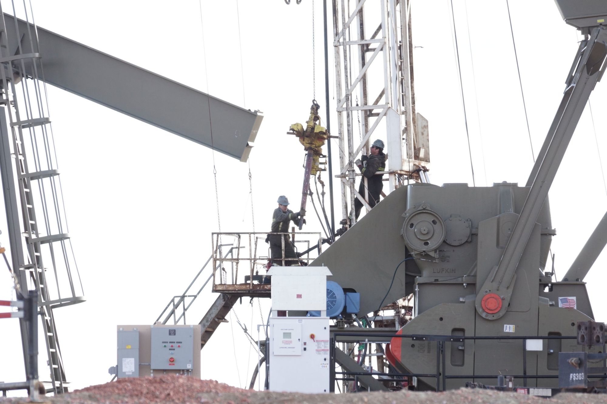 Two-person crew working on a pumping unit
